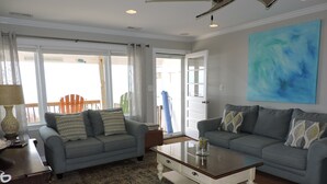 A living room with two grey sofas, a coffee table, and a large abstract painting on the wall. - Bright 3BR Beach Home with Deck & Ocean Views (Emerald Isle)