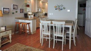 A kitchen with wooden cabinets, a dining table with chairs, and a small island with stools. - Bright 3BR Beach Home with Deck & Ocean Views (Emerald Isle)