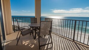 A balcony with a table and chairs, overlooking a beach with a clear view of the ocean. - Lovely 2BR Condo - Phoenix V 1115 (Orange Beach)