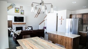 Une cuisine moderne dotée d’un îlot central, d’une table à manger en bois et d’une cuisinière encastrée.