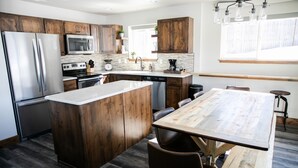 Une cuisine moderne avec des meubles en bois, des appareils électroménagers en acier inoxydable et un grand îlot central doté de sièges.