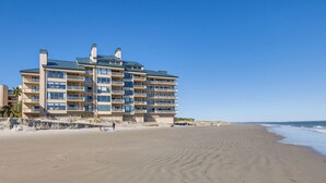 Ett hotell med flera våningar och balkonger, beläget vid en strand med sandstrand och utsikt över havet.