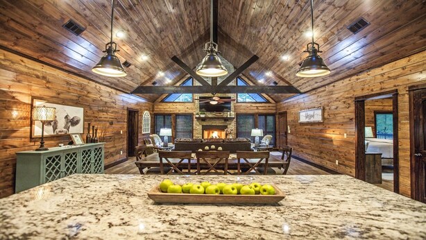 A spacious room with a large wooden ceiling, a fireplace, and a marble island with apples. - Choctaw Wind: Luxurious, Outdoor Furniture, Shuffleboard, Large Hot Tub🛋️🛁🔥 (Broken Bow)