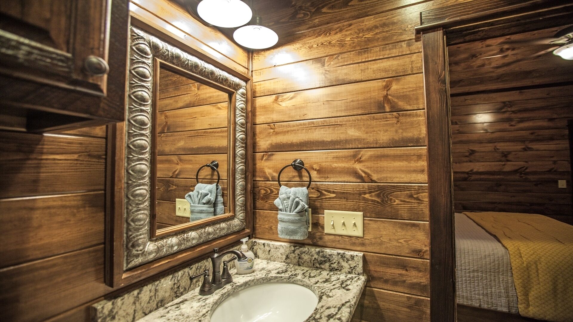 A bathroom with wooden paneling, a marble sink, and two towels hanging on towel rings.
