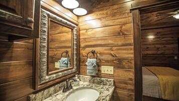 A bathroom with wooden paneling, a marble sink, and two towels hanging on towel rings.
