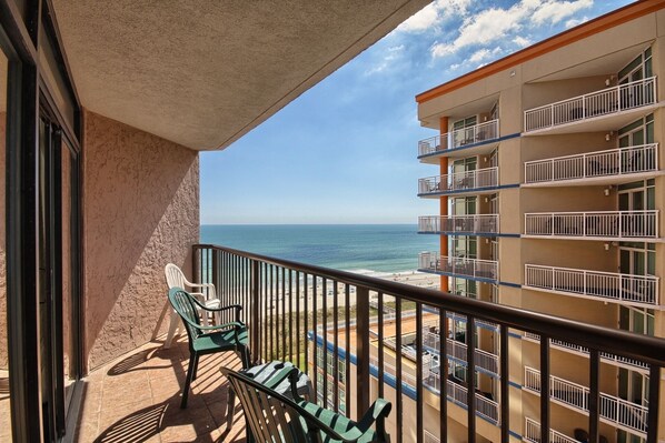 Un balcon avec vue sur la plage et l’océan, comprenant une chaise et une table.