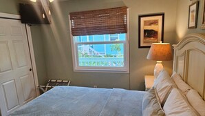 Ein Schlafzimmer mit Bett, einem Fenster mit Aussicht, einer Nachttischlampe und einem Deckenventilator.