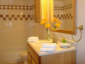 Een bad/douchecombinatie, een haardroger, handdoeken, zeep