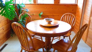 Una mesa de comedor de madera con cuatro sillas, rodeada de plantas en macetas.