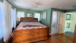 Un dormitorio con cama de madera, ventilador de techo y puerta que da a otra habitación.