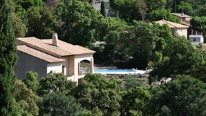 Una villa con piscina rodeada de árboles frondosos.