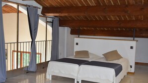 Un dormitorio con techo de madera, un balcón con cortinas y una cama con dos almohadas.
