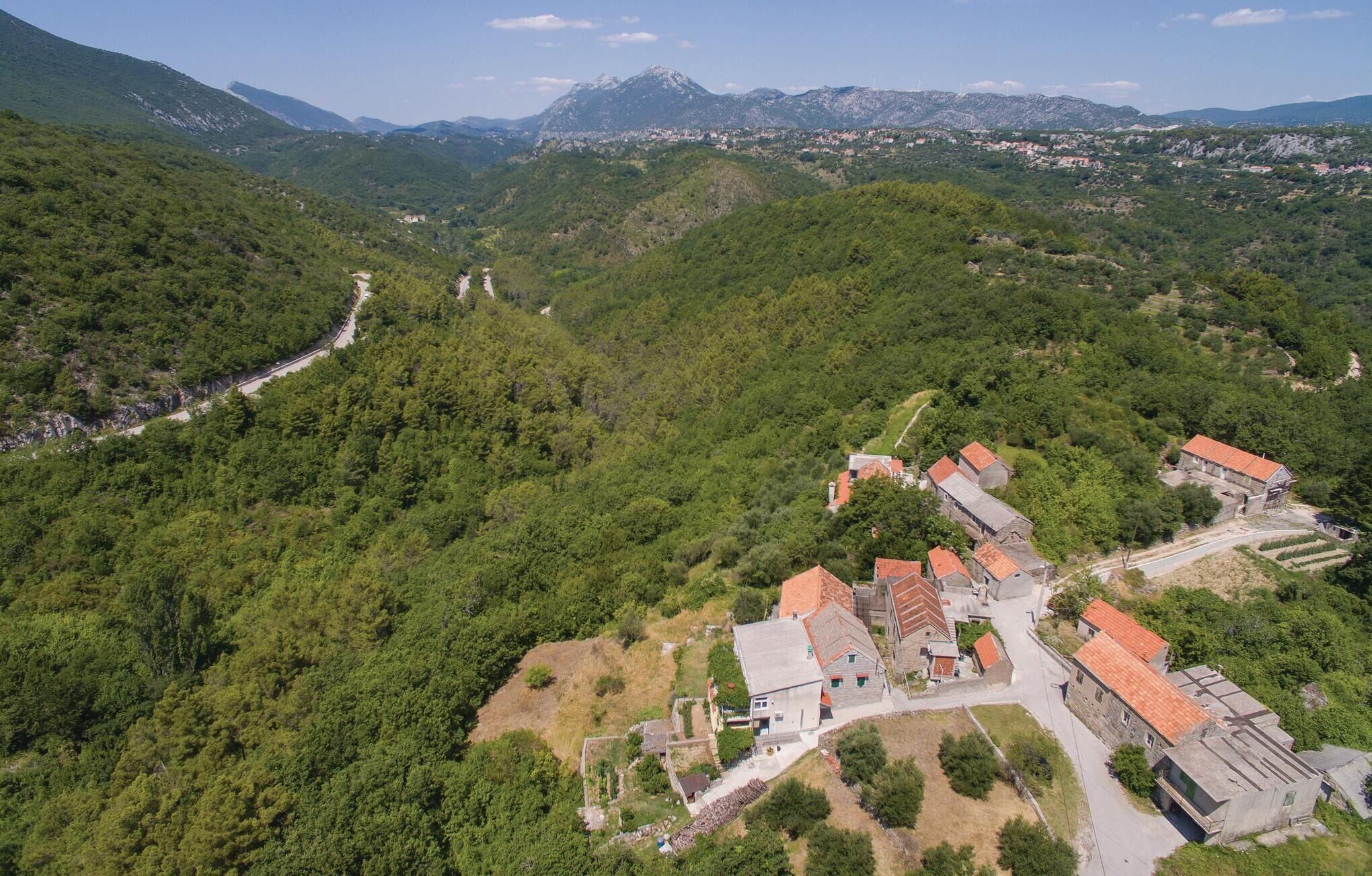 A mountainous village with traditional stone buildings and a winding road.