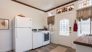 Una cocina equipada con refrigerador, lavadora, secadora y un ventanal con vidrieras.