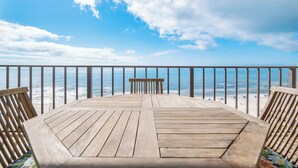 A wooden deck with a table and chairs overlooking a beach.