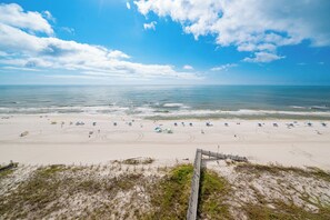 A beach with umbrellas and people, a wooden boardwalk, and a clear sky. - Phoenix 3 ~ Two Bedroom ~ Condo 3104 ~ (Orange Beach)