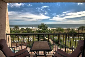 A balcony with a table and chairs overlooking a beach with umbrellas and lounge chairs. - Oceanfront Executive Suite w/ Great View + Official On-Site Rental Privileges (Myrtle Beach)