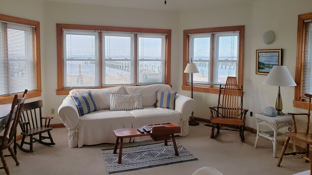 A living room with a white sofa, rocking chairs, a coffee table, and a ceiling fan.