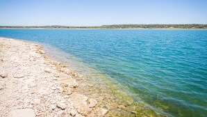 A clear view of a rocky shoreline with calm blue waters and a distant landmass. - Ledgerock Pointe: Private 3/2 Canyon Lake Waterfront + Panoramic Views + Ping Pong + Fenced Yard (Canyon Lake)