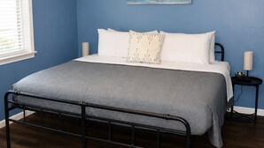 Ein Schlafzimmer mit Bett, Deckenventilator, Gemälde und Nachttisch.