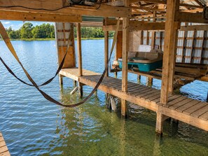A wooden dock extending over water with a boat and storage containers.