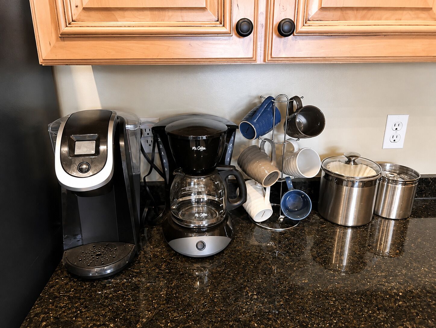 Un comptoir de cuisine avec une machine à café, une cafeti ère et plusieurs tasses.