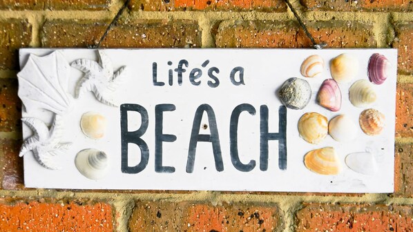 Un letrero con el texto 'Life's a BEACH' rodeado de conchas marinas.