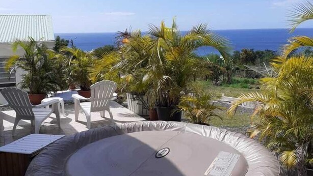 Ein Whirlpool auf einer Terrasse mit Blick auf den Ozean und Palmen.