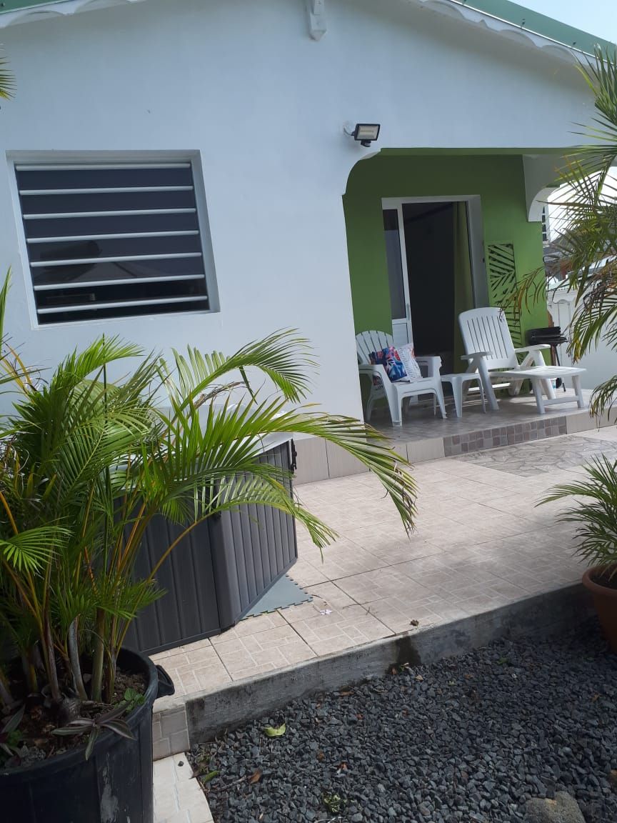 A house with a covered patio area, a window with horizontal blinds, and outdoor seating.