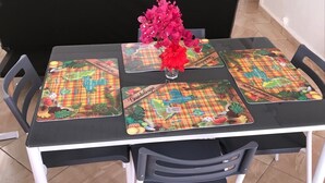 Ein Esstisch mit schwarzem Tischlein und bunten Platzsets mit Weltkarten- und Früchtemotiv.