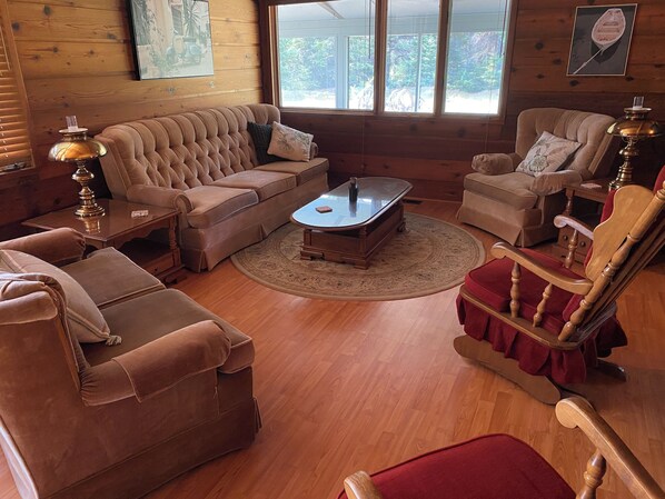 Un salon chaleureux avec un canapé d’angle marron, une table basse en bois et un fauteuil rouge.