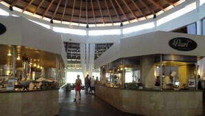 A spacious indoor area with a high ceiling and a central open space. There are two counters with signage, one labeled "Pearl."