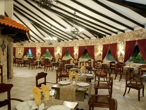 Ein Restaurant mit Steinwänden, roten Vorhängen und Holztischen und -stühlen.