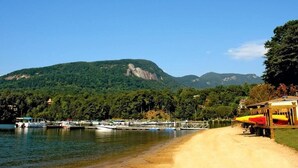 Una playa con barcos, un sendero de tierra y montañas al fondo.