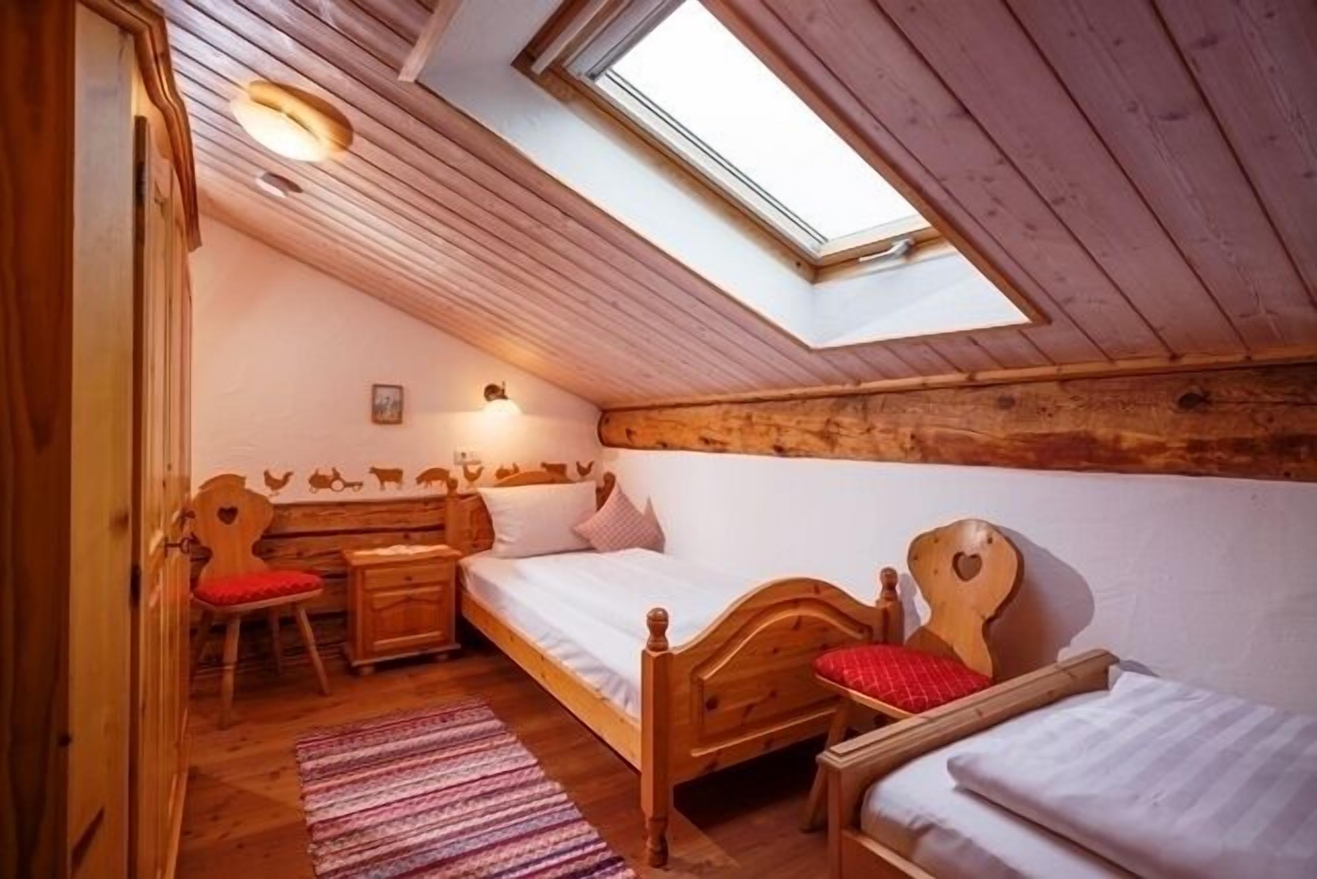 A cozy attic bedroom with a skylight, wooden furniture, and a rustic decor.