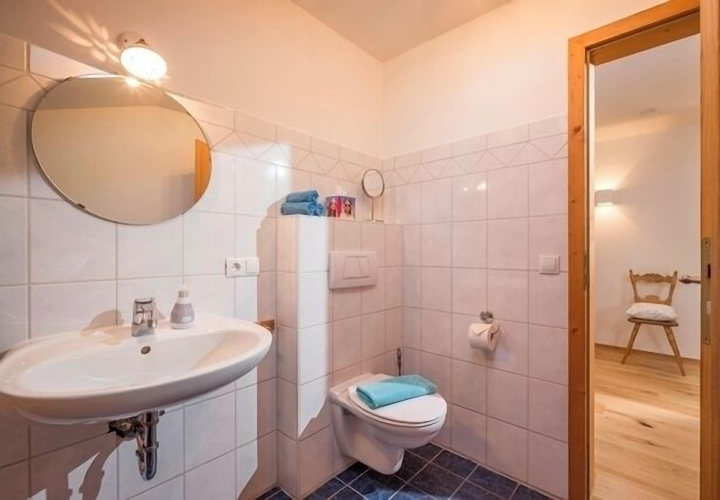 Une salle de bain avec un lavabo, des toilettes, un miroir et une porte en bois.