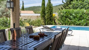 An outdoor dining area with a pool in the background.