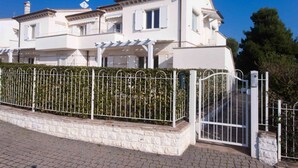 A two-story residential building with a white exterior, a gated entrance, and a stone foundation. - S018 - Sirolo, brand new three-room apartment in stone with right garden (Sirolo)