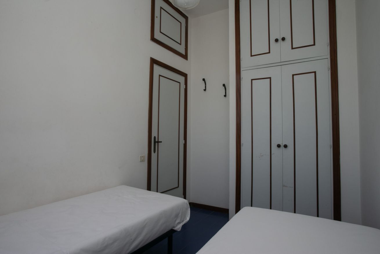 A room with two single beds, a wardrobe, and a door with a handle.