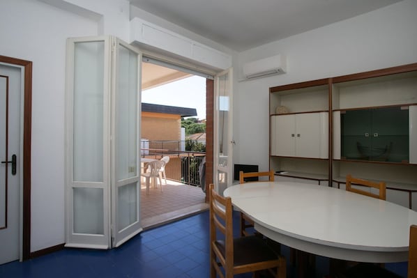 Puerta corrediza abierta que da a un balcón con mesa y sillas.
