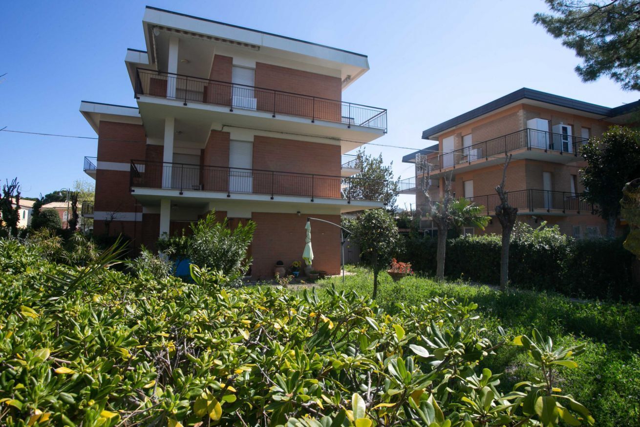 Een meerlaags woongebouw met balkons en een tuin op de voorgrond.