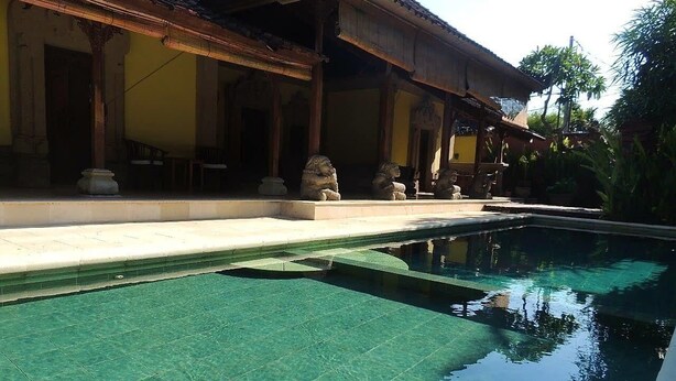 Un bâtiment de style traditionnel doté d’une piscine, de statues en pierre et d’une terrasse carrelée.