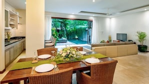 Un espace de repas moderne avec une table dressée pour quatre personnes, un canapé et un téléviseur dans le salon.
