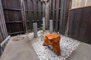 A wooden bench with a unique design, surrounded by a gravel area and a wooden fence.