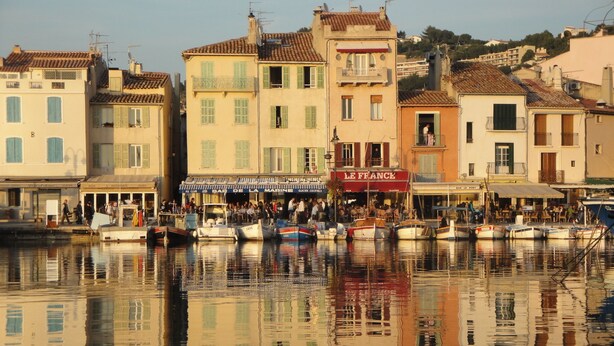 Una costa con edificios, un bar y barcos amarrados.