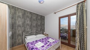 Un dormitorio con cama, mesita de noche y vistas a través de un ventanal.