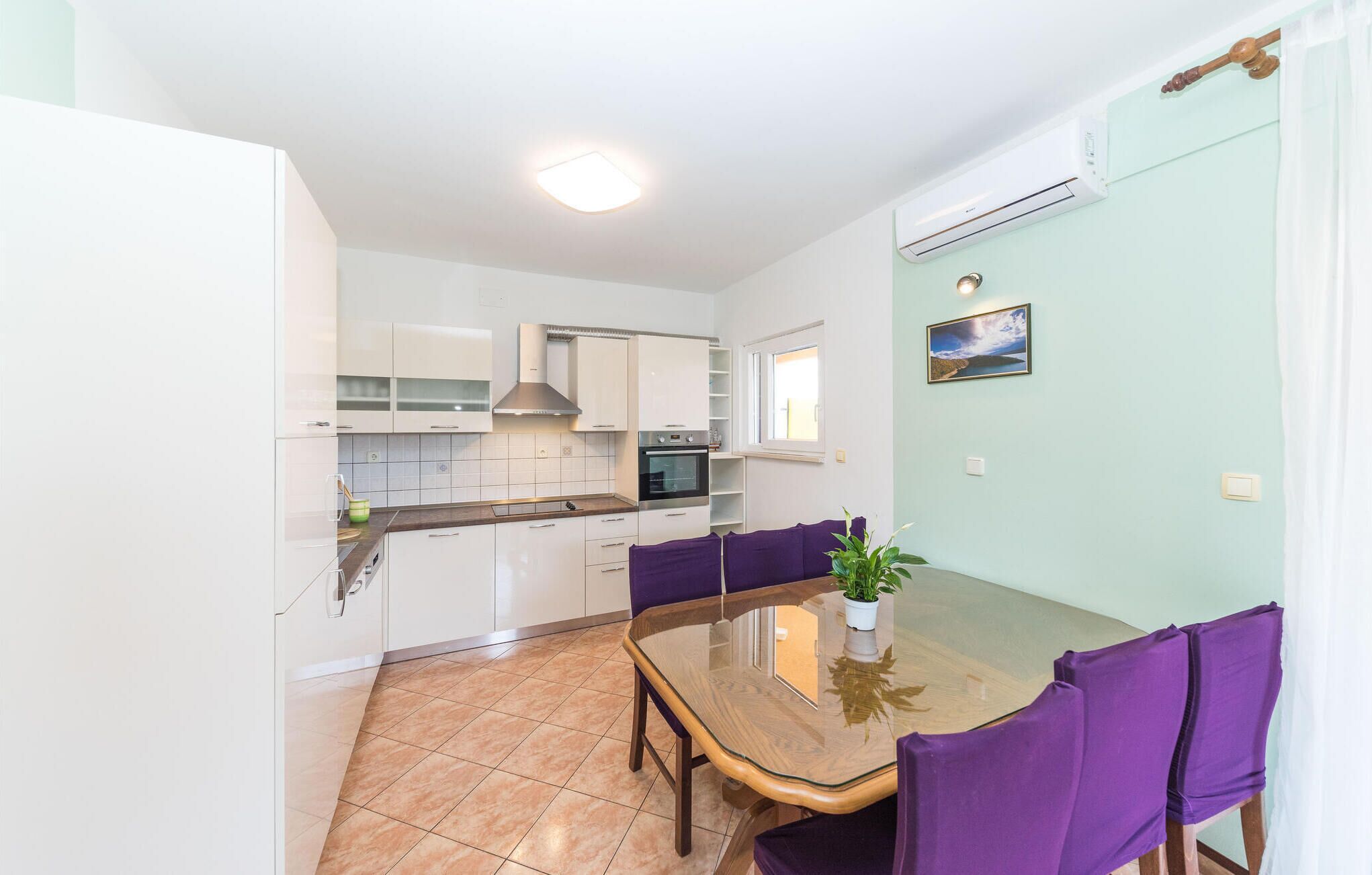 A compact kitchen with white cabinets, a built-in oven, and a window.