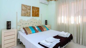Una camera d'albergo con un letto, un comodino, una lampada e una finestra con tende.