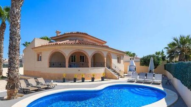 Una villa in stile mediterraneo con piscina, lettini prendisole e una scala che conduce all'ingresso.