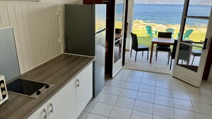 A kitchen with a view of the sea, a dining area with chairs, and a table. - Seafront apartment for 4 people in the heart of nature (CALCATOGGIO)